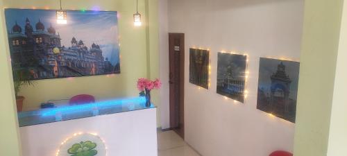 a room with three pictures on the wall and a vase with flowers at ADH Amilia Nest in Mysore