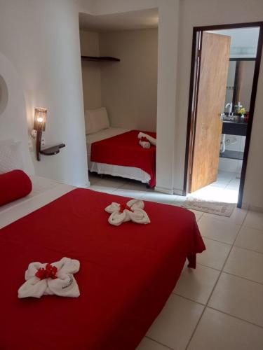 a bedroom with a red bed with towels on it at Vila Verissimo in Jericoacoara