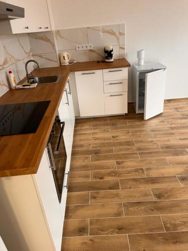 a kitchen with white cabinets and a wooden floor at Apartmány za kostelem in Husinec
