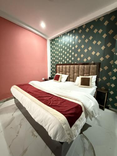 a bedroom with a large bed with a red wall at Hotel Ayodhya International in Ayodhya