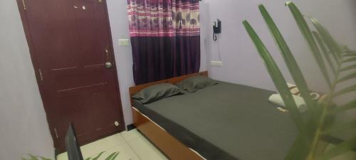 a small bedroom with a bed and a curtain at ADH Amilia Nest in Mysore