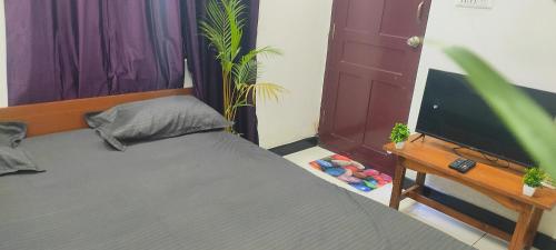 a bedroom with a bed and a flat screen tv at ADH Amilia Nest in Mysore