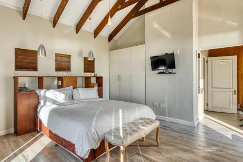 a bedroom with a large bed and a tv at Manor on the Bay in Gordonʼs Bay