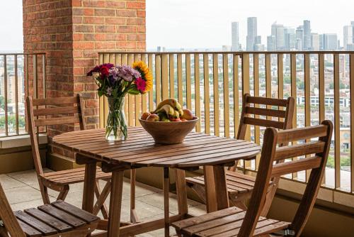 a wooden table with a bowl of fruit and a vase of flowers at Bermondsey Apartments By Sleepy Lodge in London