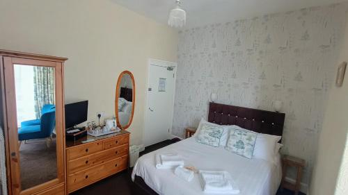 a bedroom with a bed and a mirror and a dresser at Hazeldene Guest House - with Free Offsite Health Club in Bowness-on-Windermere
