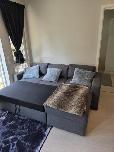 a living room with a grey couch with pillows at Two bedrooms Luxury apartment with free parking in Lorenskog