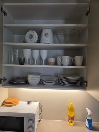 a kitchen shelf with plates and bowls and a microwave at Two bedrooms Luxury apartment with free parking in Lorenskog