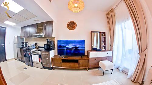 a kitchen with a large tv on a wooden desk at Cozy Urban Studio - Peach Bliss Haven in Abu Dhabi