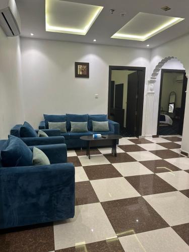 a living room with blue couches and a checkered floor at قصر الورد للشقق المخدومة in Taif