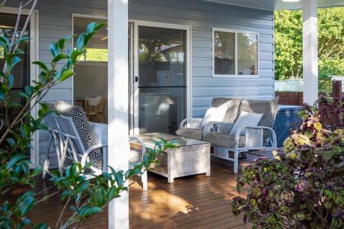 a porch with wicker chairs and a table at Magnolia Homestead in Coffs Harbour