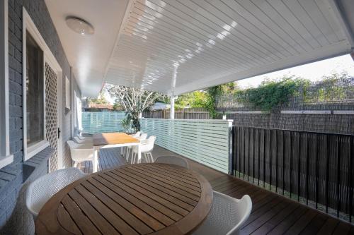 a patio with a wooden table and chairs on a deck at Magnolia Homestead in Coffs Harbour