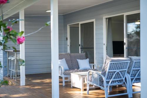 a porch with chairs and a coffee table on a house at Magnolia Homestead in Coffs Harbour