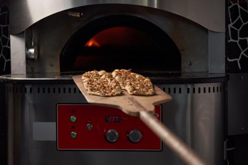 two pizzas on a cutting board in an oven at Hotel Grand Kaptan - Ultra All Inclusive in Alanya