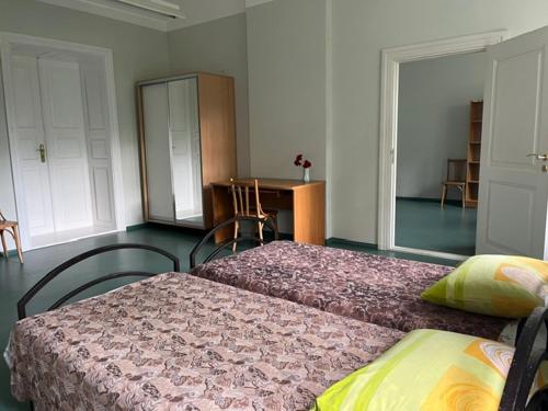 a bedroom with two beds and a desk in it at Naukšēnu muiža in Naukšēni