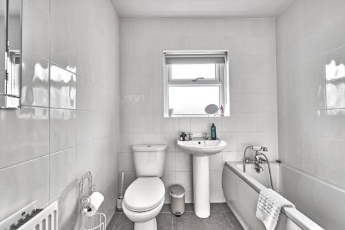 a white bathroom with a toilet and a sink at Loughside Lodge - Fermanagh 5 bed waterside bungalow in Culky