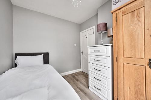 a bedroom with a white bed and a dresser at Loughside Lodge - Fermanagh 5 bed waterside bungalow in Culky