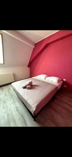 a bed in a room with a pink wall at Les Ailes de Morphée in Villé