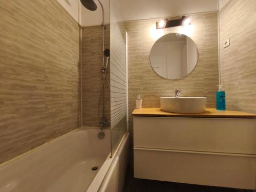 a bathroom with a sink and a mirror and a tub at 3 Chambres Cosy Parking Gratuit Wifi 6 Personnes in Mont-Saint-Aignan