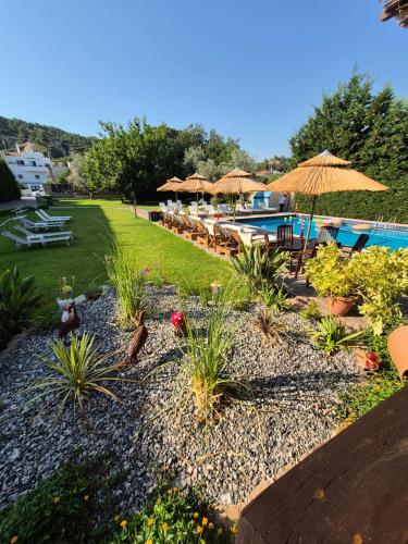 a garden with tables and umbrellas and a pool at Maritina Apartments in Ixia