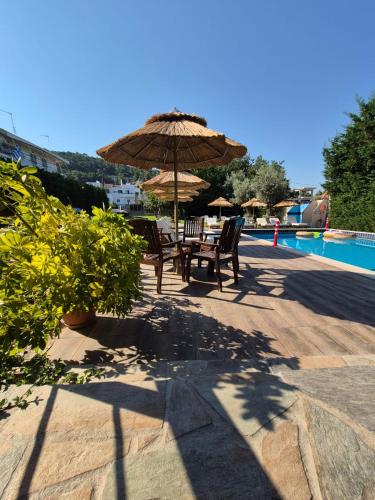 a table and chairs under an umbrella next to a pool at Maritina Apartments in Ixia