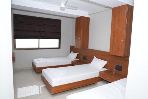 a bedroom with two beds and a window at Hotel Yashraj Regency in Sangamner