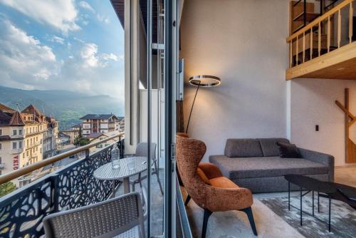 a balcony with a couch and a table and chairs at Hotel Kreuz & Post Grindelwald in Grindelwald