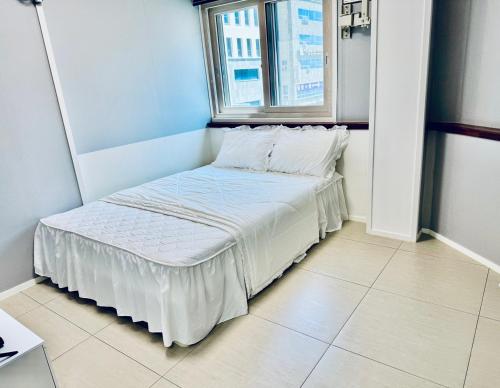 a small bed in a room with a window at Lime Hostel in Yeosu
