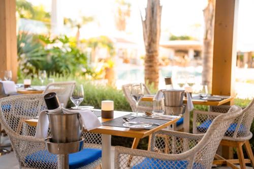 an outdoor restaurant with tables and chairs with wine glasses at Sentido Kyknos Beach Adults Only in Malia