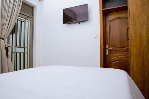a bedroom with a bed and a television on a wall at Velvet Suites in Kigali