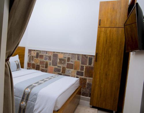 a bedroom with a bed and a dresser in a room at Velvet Suites in Kigali