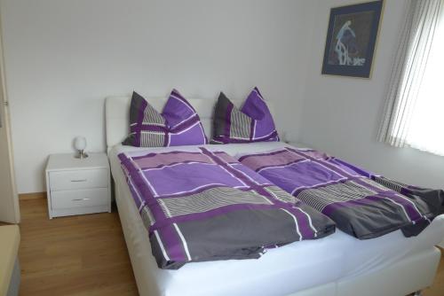 a bed with purple and black sheets and pillows at Ferienwohnung Kusternik in Velden am Wörthersee