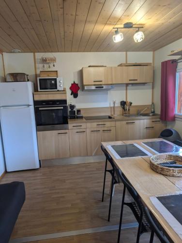 a kitchen with a table and a white refrigerator at Chalet de 10 pers avec Suite Parental au pied des Pistes in Saint-Léger-les-Mélèzes