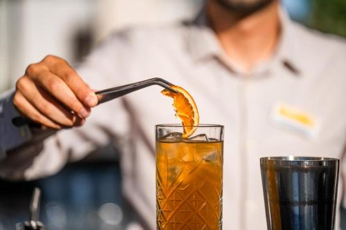 a man is stirring a drink with a spoon at Sentido Kyknos Beach Adults Only in Malia