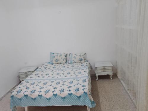 a bedroom with a bed with a blue and white blanket at Location Kelibia in Kelibia