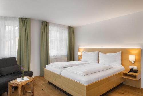 a bedroom with a large bed and a couch at Hotel OXA - Easy Escape in Hittisau