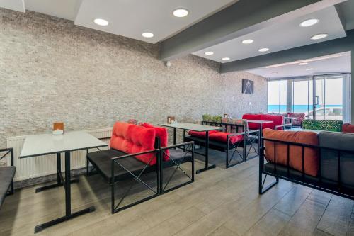 Un restaurante con sillas y mesas rojas y ventanas. en Niko Airport Black Sae Hotel, en Arnavutköy