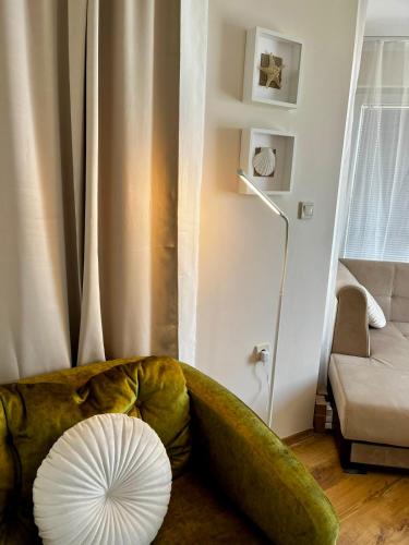 a living room with a green couch and a fan at Blue Bay House in Nesebar