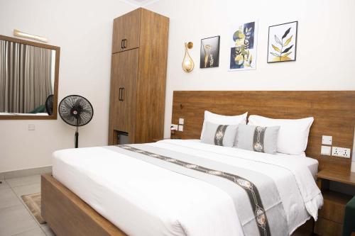 a bedroom with a large white bed with a wooden headboard at Velvet Suites in Kigali