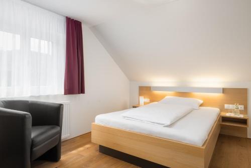 a bedroom with a bed and a chair and a window at Hotel OXA - Easy Escape in Hittisau