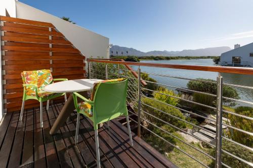 a balcony with a table and chairs overlooking a river at Vlei Cove Guesthouse in Cape Town