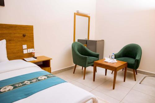a hotel room with a bed and two chairs and a table at Velvet Suites in Kigali