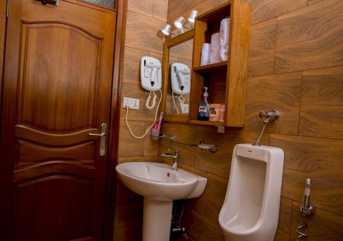 a bathroom with a sink and a toilet and a urinal at Velvet Suites in Kigali