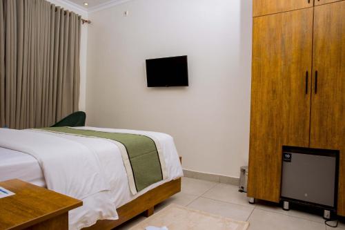 a bedroom with a bed and a tv on the wall at Velvet Suites in Kigali