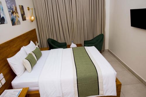 a bedroom with a large bed with two green chairs at Velvet Suites in Kigali