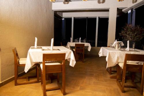 a dining room with three tables with white tablecloths at Velvet Suites in Kigali