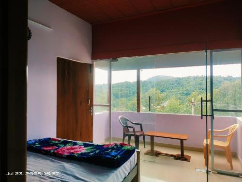 a room with a bed and a table and a window at Sky View Resort in Yercaud