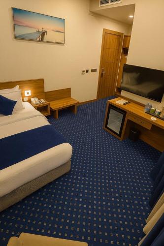 a hotel room with a bed and a flat screen tv at Nova Sky Hotel in Erbil