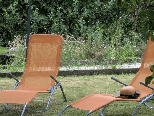 two chairs sitting in the grass with a hat on them at Gîte des Lilas in Stenay