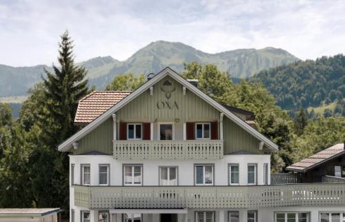 a large white house with mountains in the background at Hotel OXA - Easy Escape in Hittisau