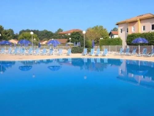 une grande piscine avec chaises et parasols dans l'établissement Appartement avec Piscine, Tennis et Terrasse à Soustons - FR-1-379-155, à Soustons